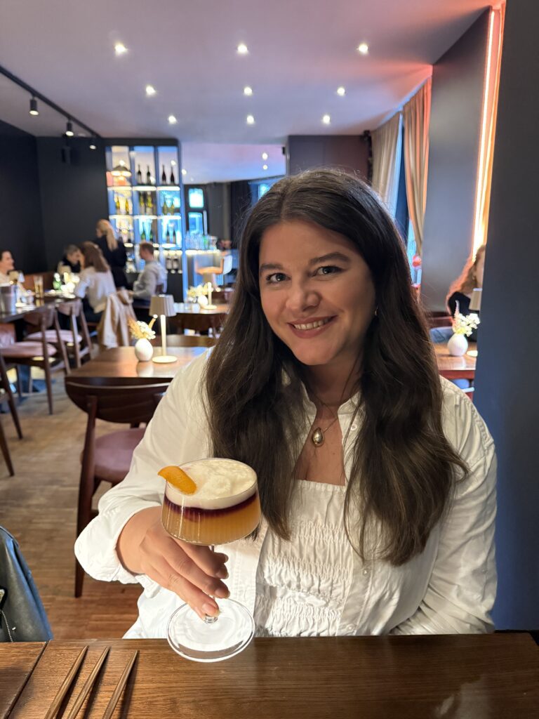 Laura im Restaurant mit einem Cocktail in der Hand