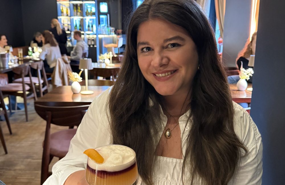 Laura im Restaurant mit einem Cocktail in der Hand